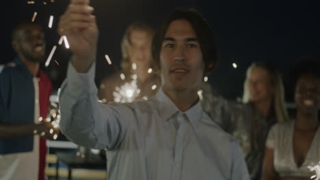 friends celebrating on a rooftop at night with sparkler