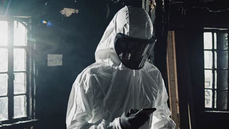 a person in a hazmat suit checks a device in a dimly lit room