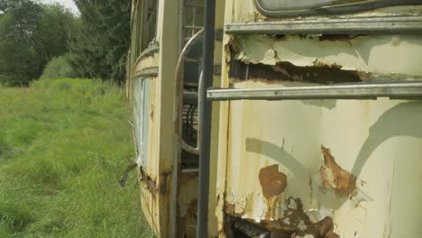 un viejo autobús oxidado abandonado en un campo de hierba verde