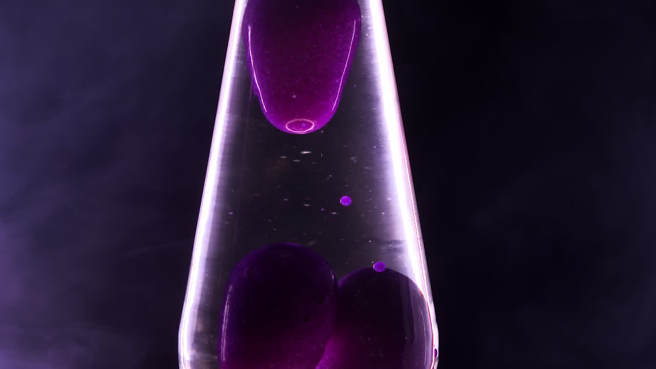 Close-up of a purple lava lamp with cannabis smoke swirling around it