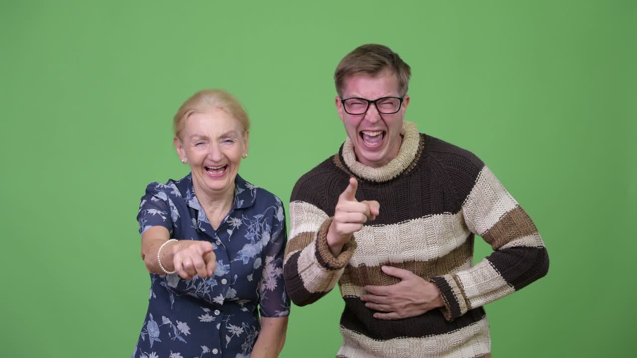 Happy grandmother and grandson laughing while pointing at camera together