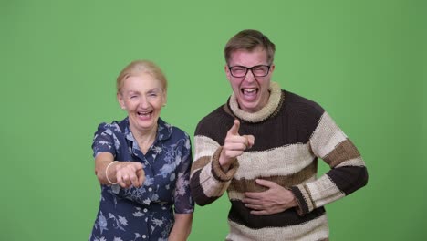 happy grandmother and grandson laughing while pointing at camera together