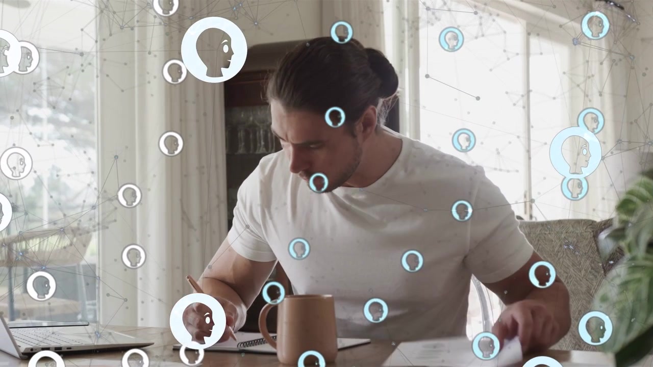 Uomo con chignon che legge un giornale, si protende verso il laptop e prende appunti per affari, con nodi di rete che oscurano.