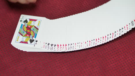 cierre en cámara lenta de una baraja de cartas que se extiende sobre una mesa de juego roja