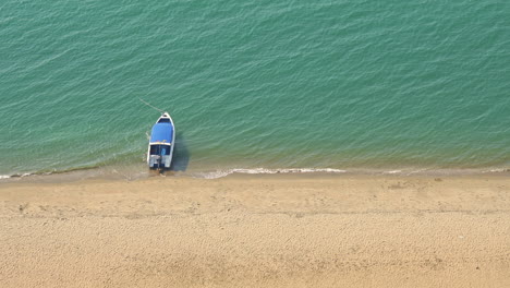 a high angle, a single boat anchored at a golden sandy beach