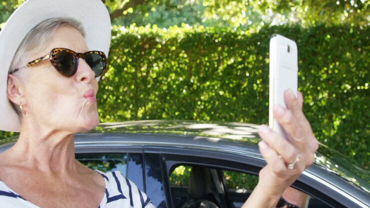 Uomo anziano che guarda una donna mentre si scatta un selfie