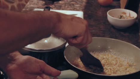 candid kitchen scene, adding water to a pan of roasted onions and flour to make gravy sauce