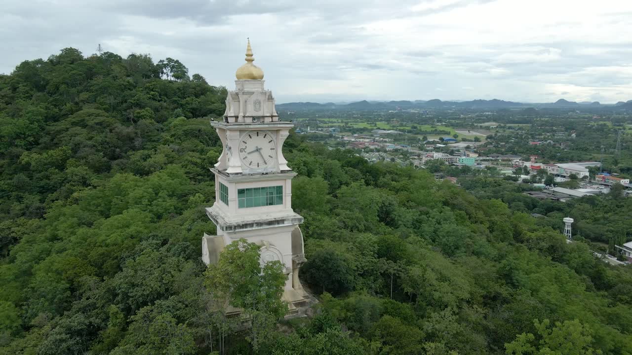 torre del reloj ubicada en una colina entre los árboles del bosque en tailandia