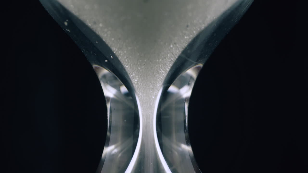 砂がガラスの時計の中に落ちる 時間マクロ