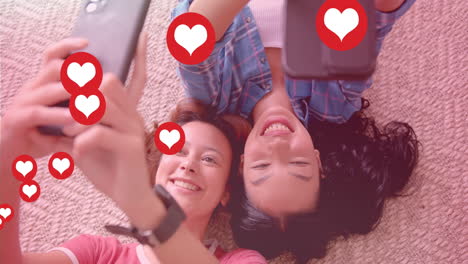 taking selfies and smiling, two women with heart icons animation over them