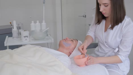 A Woman Lies on a Spa Bed for a Face and Head Massage Spa Treatment By a Masseuse. A woman lies on a spa bed for a face and head massage spa treatment by a masseuse. The concept of wellness, stress relief and facial rejuvenation