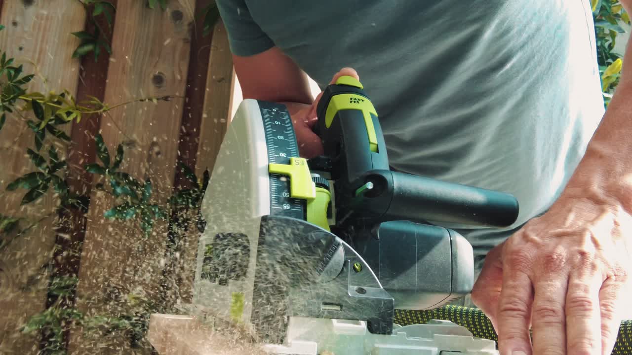 slomo close up man con sierra circular moderna con sierra guía a través de un trozo de madera