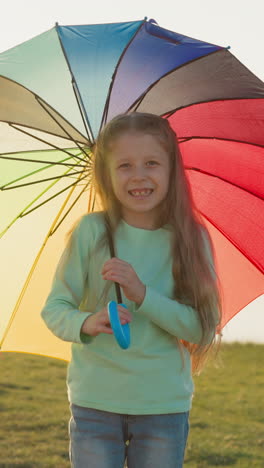 girl twirls parasol under rain and sunlight. raindrops provide serene soundtrack to child fluid movements. magical spectacle along riverbank