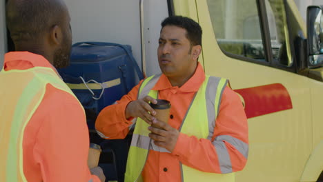 latin ambulance driver drinking coffee and talking with his black colleague