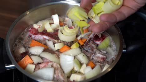 leek added to bone broth and vegetable pan, slow motion