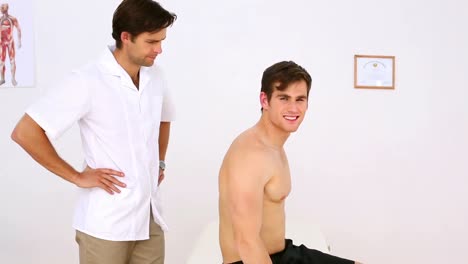 Physiotherapeut-Untersucht-Die-Verletzte-Schulter-Des-Patienten-Und-Lächelt-In-Die-Kamera