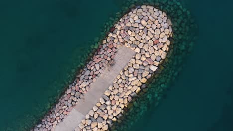 imágenes aéreas de un rompeolas hecho de rocas en las aguas muy claras del mar rojo