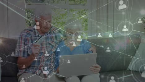 animación de la red de conexiones con iconos sobre una pareja caucásica mayor usando una computadora portátil
