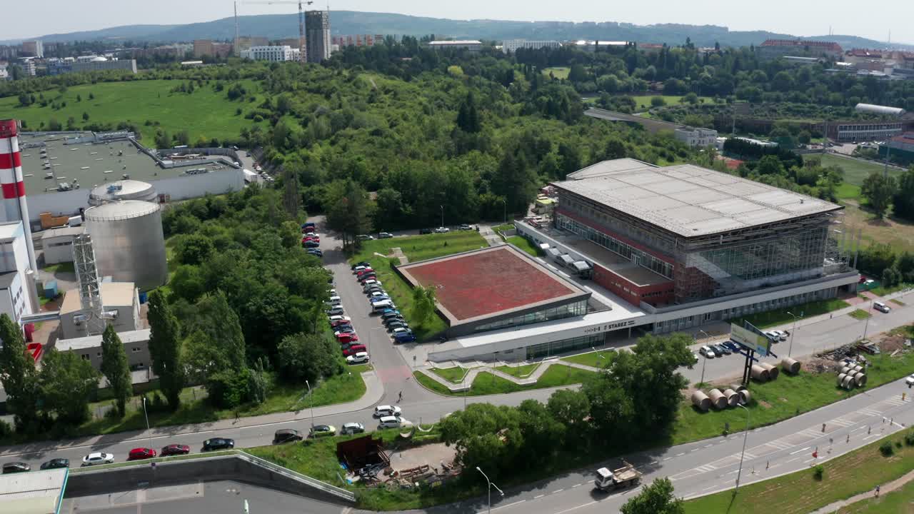 jib down drone shot of public indoor swimming pool with parking lot in brno city