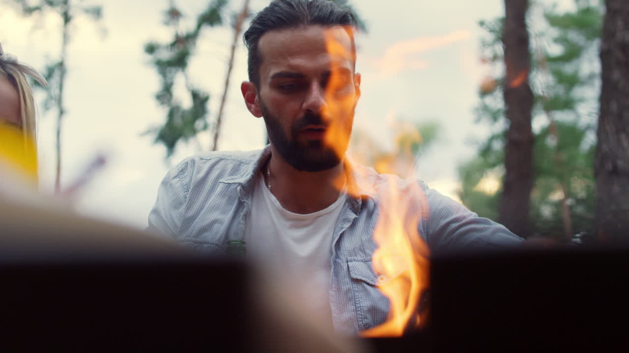 Uomo serio che usa utensili da cucina all'aperto. Prepara cibo per il barbecue all'esterno.