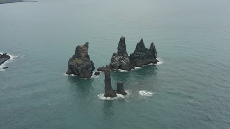 mythical rock formation reynisdrangar in calm water of atlantic ocean