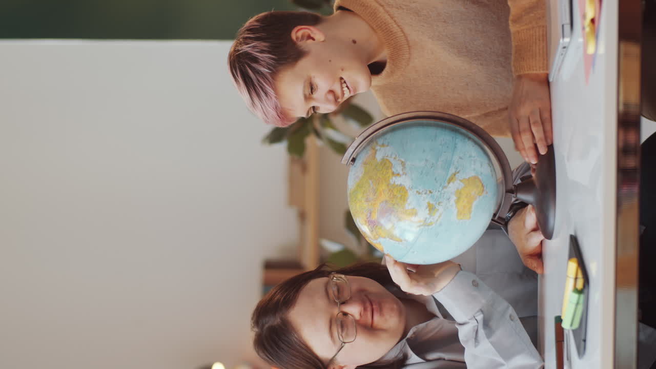 dos mujeres aprendiendo sobre geografía con un globo