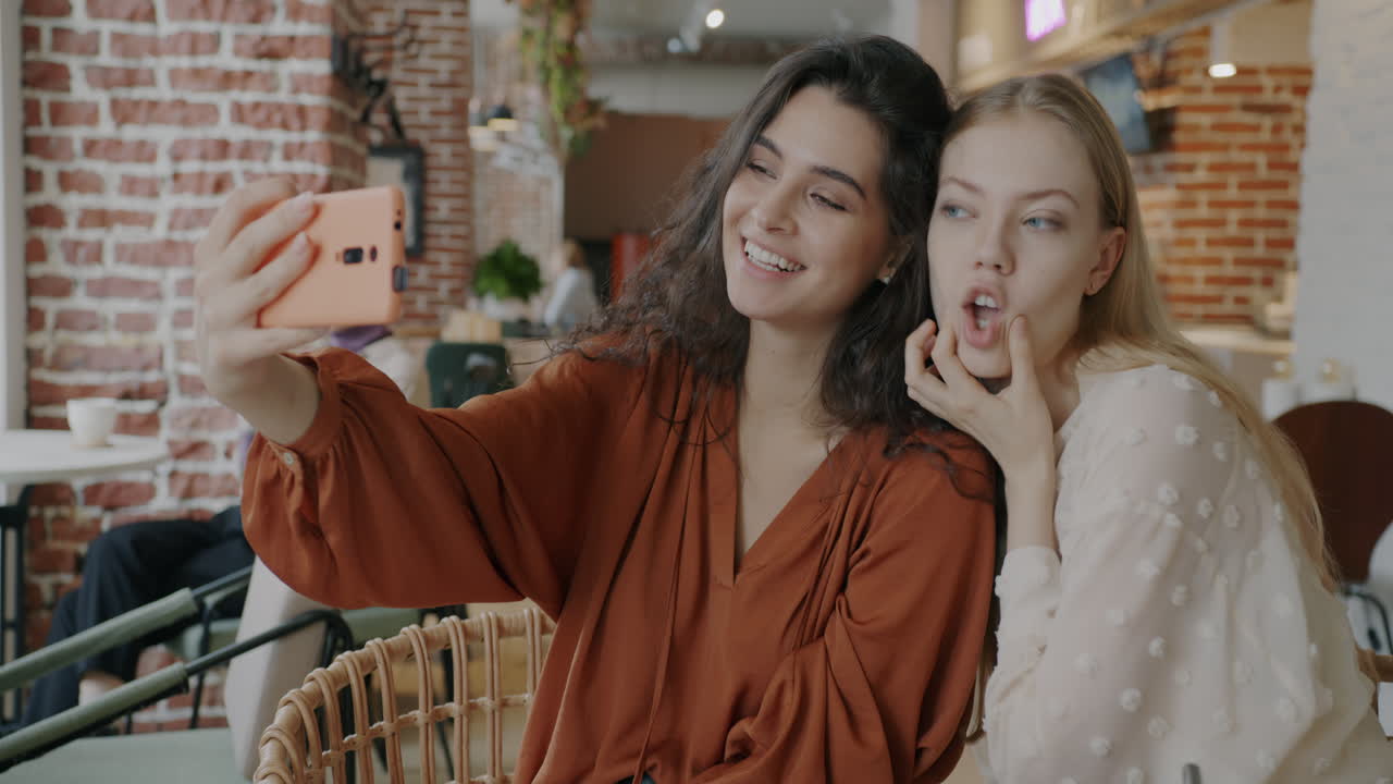 dos amigos felices tomando una selfie en un café