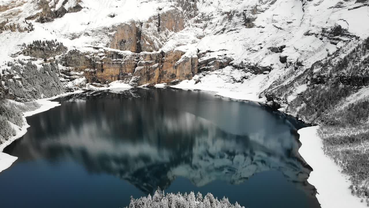 Veduta aerea del lago Oeschinensee a Kandersteg, Svizzera, con un riflesso delle cime montuose in una giornata invernale