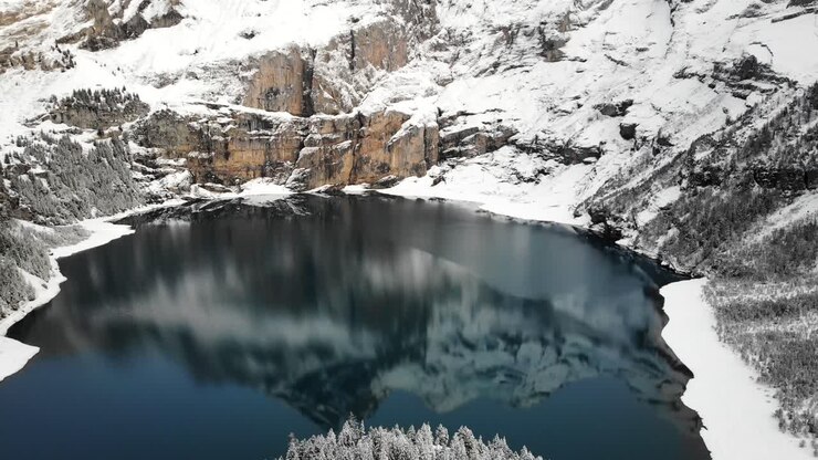 Veduta aerea del lago Oeschinensee a Kandersteg, Svizzera, con un riflesso delle cime montuose in una giornata invernale