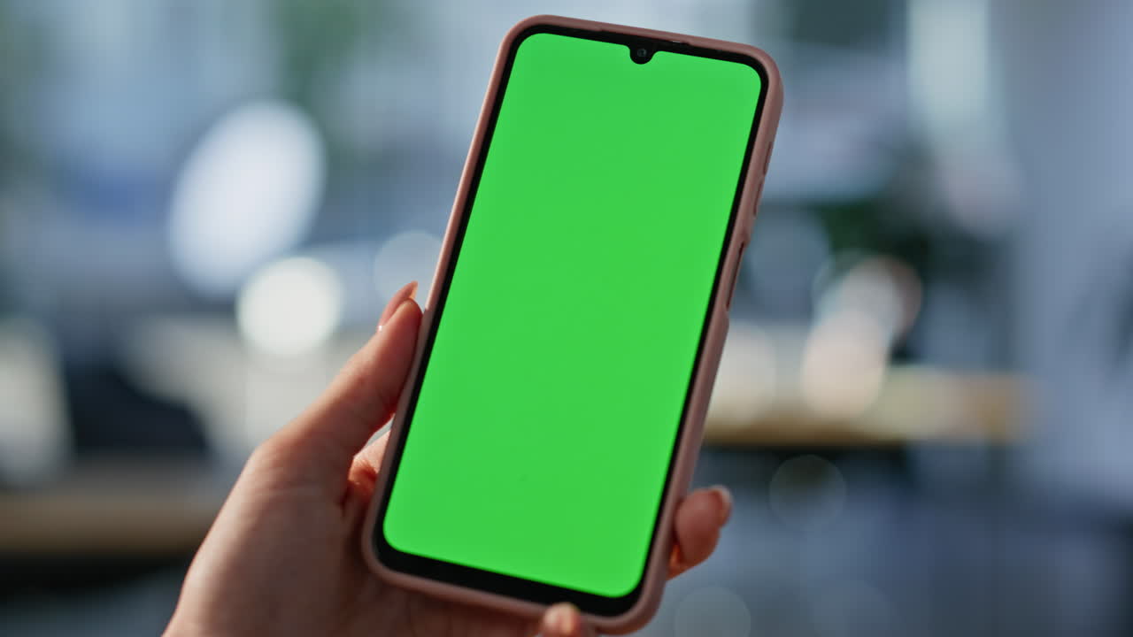 Primo piano di una mano che tiene in mano un mockup di smartphone in ufficio. Donna irriconoscibile