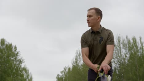 Disc-golfer-steps-onto-the-tee-and-puts-bag-down-and-checks-out-the-course---Front-view-medium-shot