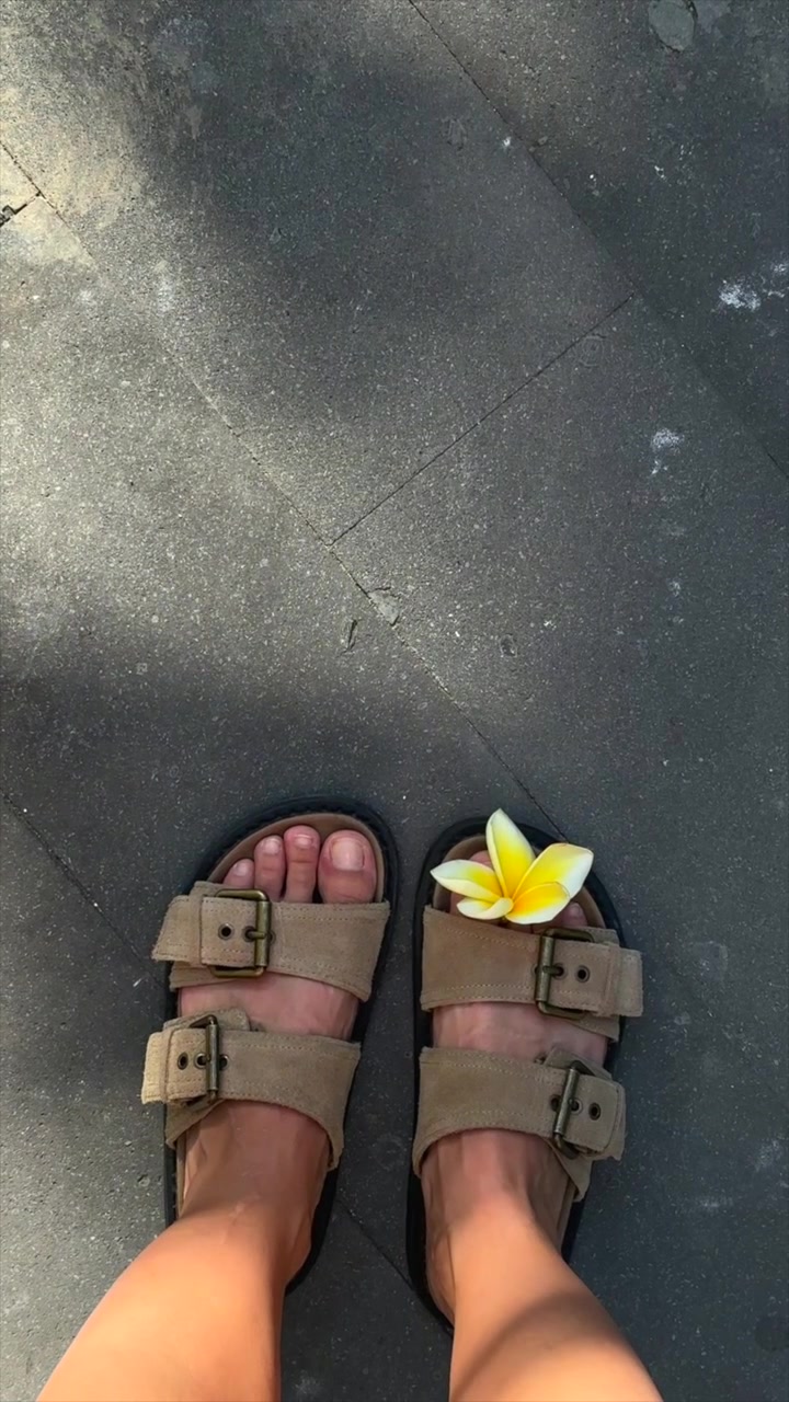 Pessoa de Sandálias com uma Flor de Jasmim-manga na Calçada