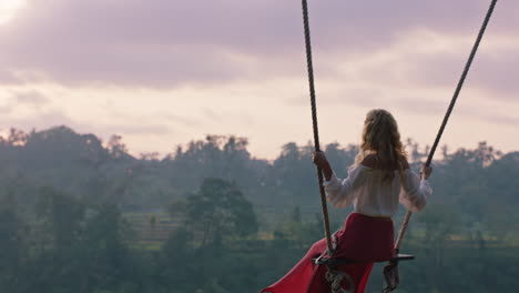 Mujer-Feliz-Balanceándose-Sobre-La-Selva-Tropical-Al-Amanecer-Sentada-En-Un-Columpio-Con-Vista-Panorámica-Disfrutando-De-La-Libertad-En-Vacaciones-Divirtiéndose-Estilo-De-Vida-De-Vacaciones-En-Cámara-Lenta