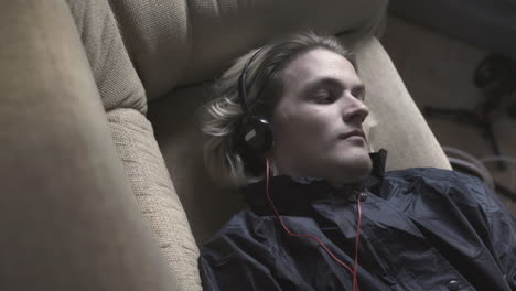 man sleeping on a couch with headphones