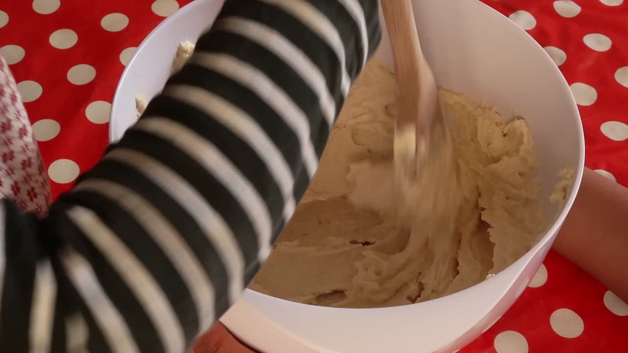 Children of African ethnicity stirring cake batter, making a cake together