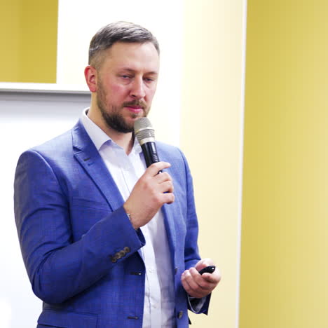 professional speaker in suit with microphone at business conference. audience listens to the lecturer at the conference hall. business and entrepreneurship.