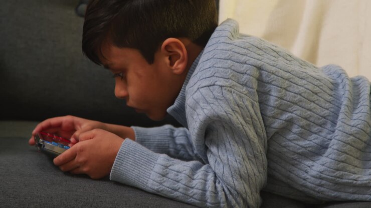 Young Boy Lying On Sofa At Home Playing Game Or Streaming Onto Handheld Gaming Device 6