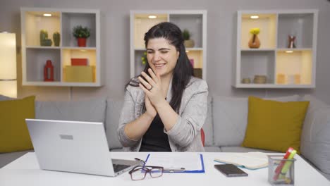 una trabajadora de oficina en casa aplaudiendo lo que ve en la computadora portátil.