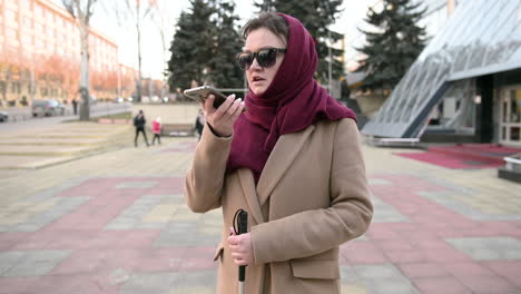 mujer ciega hablando por teléfono móvil al aire libre en un día de invierno