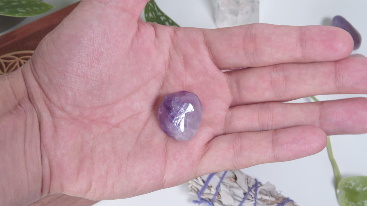 Amethyst tumbled stone in the palm of a hand