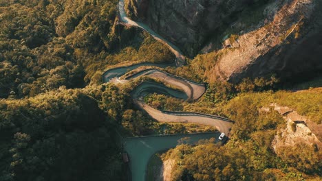 Car-passing-in-one-of-the-most-beautiful-and-dangerous-roads-in-the-world-at-sunrise,-top-down-aerial-view