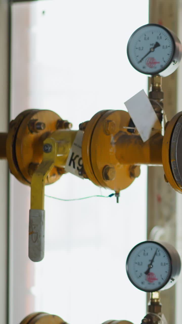 Knot on gas transporting pipeline with pressure meters and levers in mechanical house. Yellow metal pipes delivering fuel to stove and tank heating