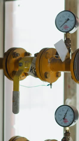 knot on gas transporting pipeline with pressure meters and levers in mechanical house. yellow metal pipes delivering fuel to stove and tank heating