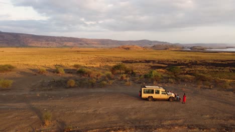 a stunning drone shot of a safari jeep parked on a hilltop with a view of lake natron in tanzania in africa during sunrise hours