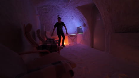 man walks into salt cave and sits on chair for halotherapy