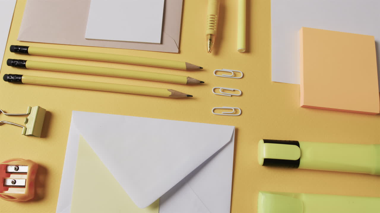 A variety of stationery items are neatly arranged on a yellow surface