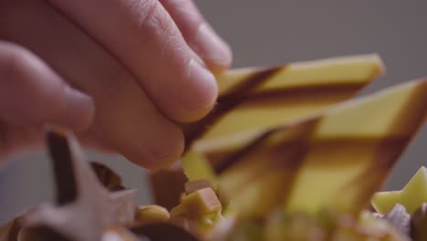 primer plano del hombre en la cocina de casa agregando decoración de chocolate al pastel recién horneado en la superficie de trabajo