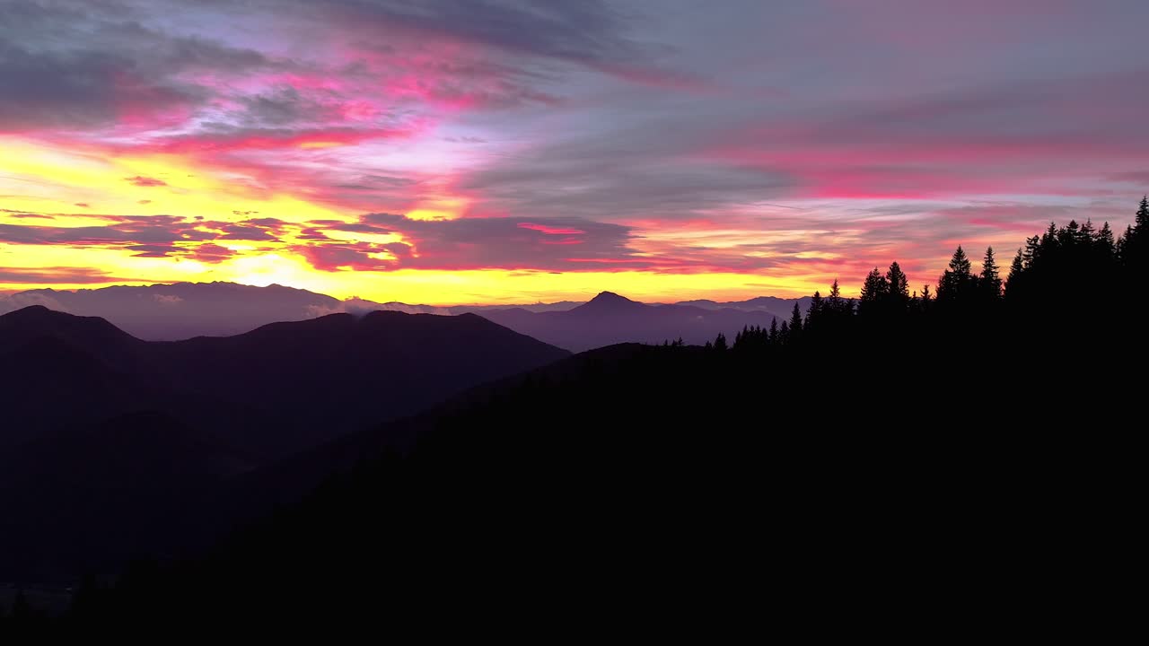Sunrise drone flight in mountainous landscape, colorful cloudy sky