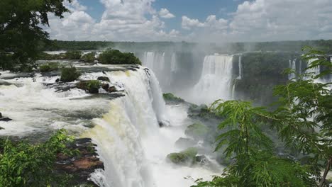 beautiful falling clear water in iguazu falls, brazil, south america, high above view of large waterfall dropping into rainforest plunge pool in colourful green jungle landscape