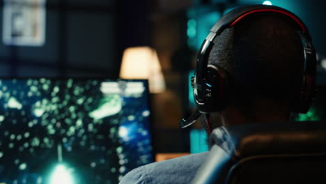 man playing sf space videogame on pc screen, putting headphones on